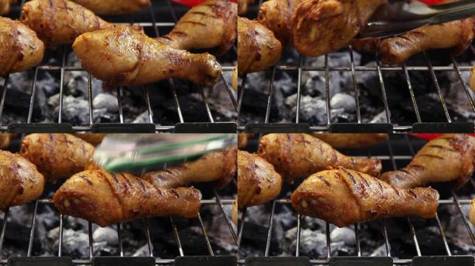 烧烤烤架上的烤鸡腿。烹饪过程。用铁钳翻转肉禽