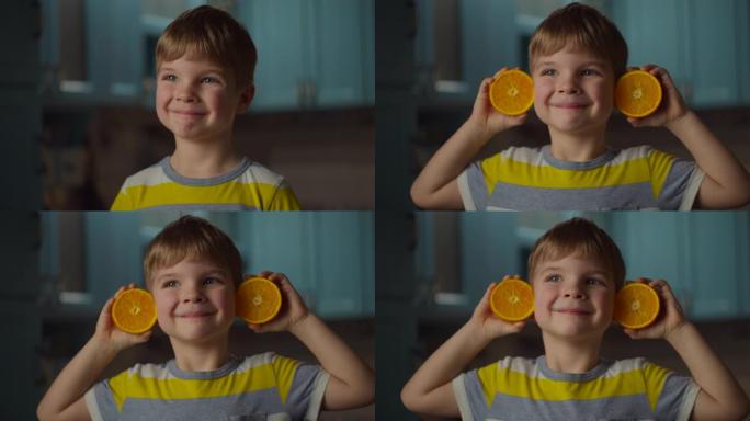 学龄前男孩手里拿着两半橙色水果，把它放在耳朵上，微笑着看着相机。橙色水果婴儿耳朵在慢动作。