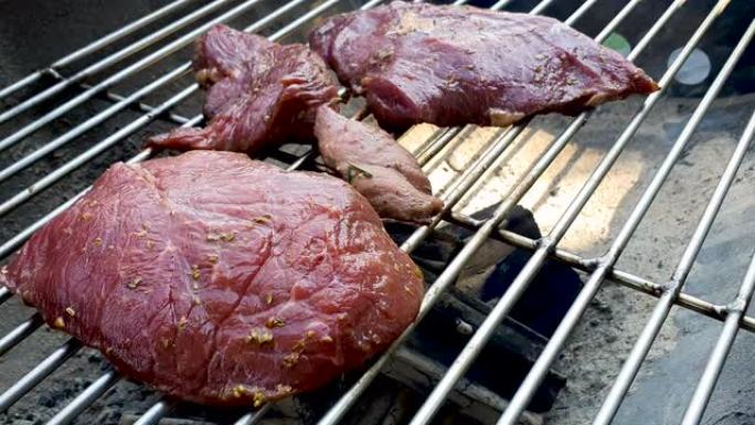 多汁的牛肉肋眼牛排放在热烤架上，用木炭和火焰
