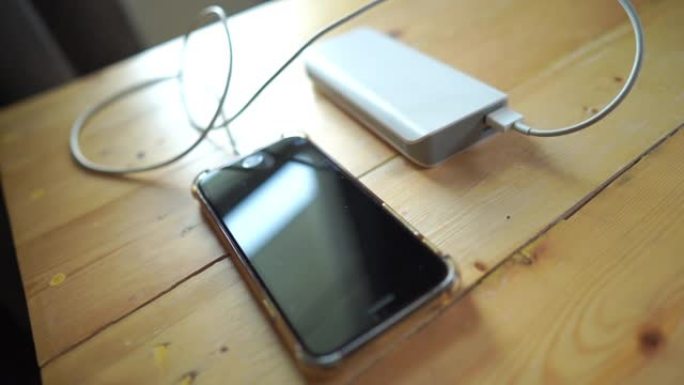 木制桌子上的带电源组电池充电器的智能手机充电