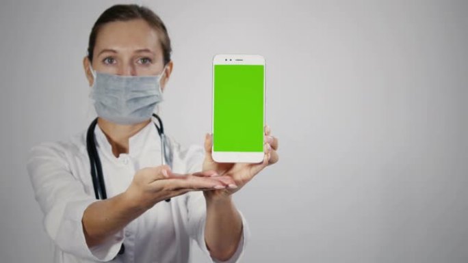 女性医疗专业人员展示带绿屏的移动智能手机。