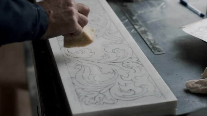雕刻师在石板上放清漆，以固定绘制的装饰品