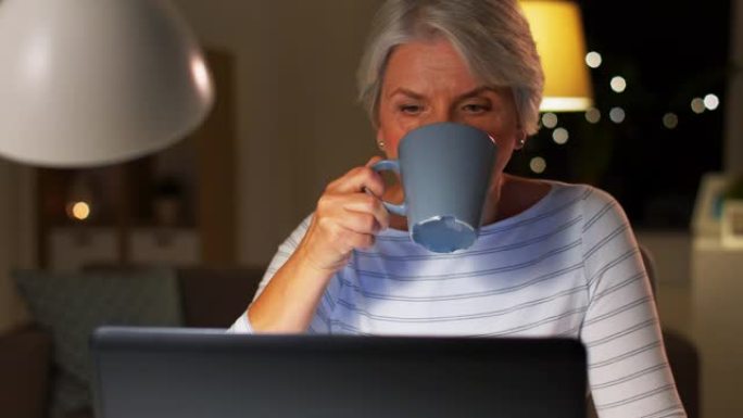 带笔记本电脑的高级女性在家喝咖啡