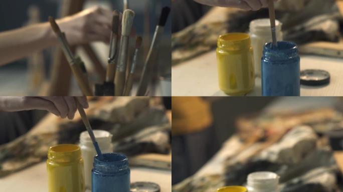 艺术家将画笔浸入油漆和绘画中