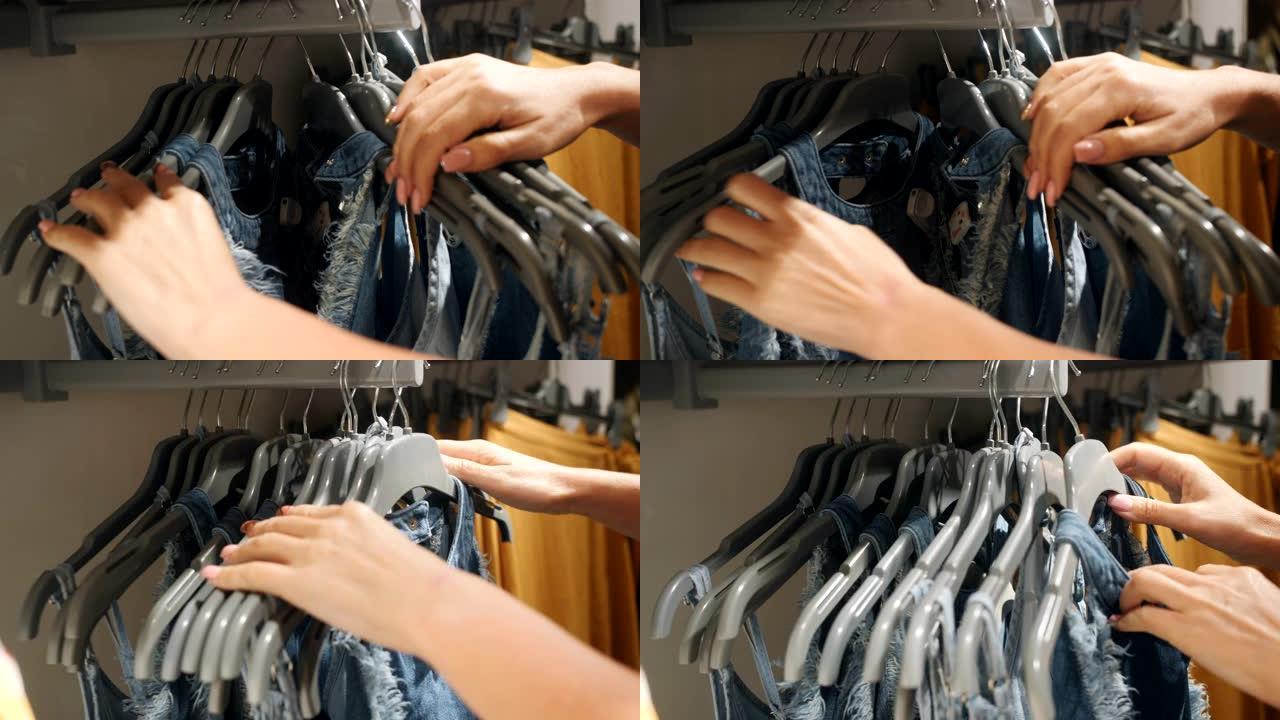 女性的手透过服装店挂在衣架上的衣服看。