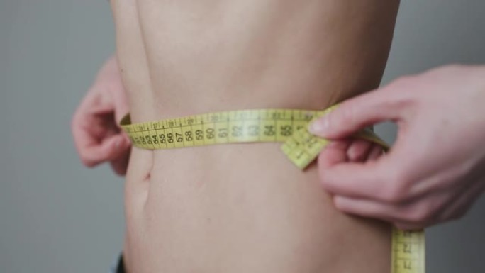 女人用磁带控制自己的措施。女人测量她的身体。减肥概念