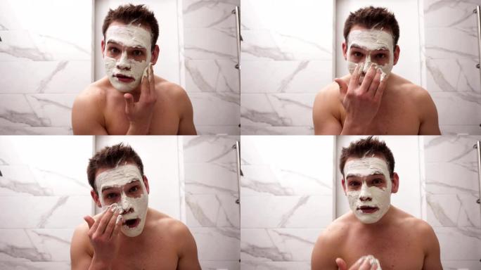 年轻英俊男子的肖像正在脸上涂上新鲜的白色厚面膜和擦洗。天然有机护肤化妆品。男人淋浴后，面部皮肤护理