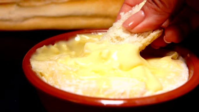 法棍面包浸在预热的圣费利西安奶酪在小陶瓷锅