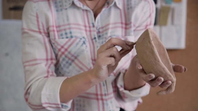 波特女人在工作室制作陶罐。用生粘土工作的成年女性