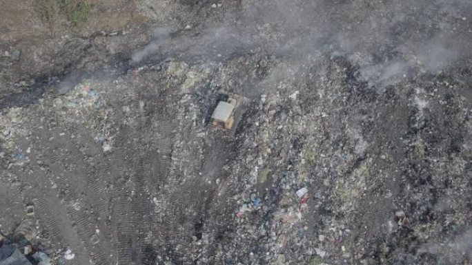无人驾驶飞机查看在垃圾场上清理的工人，推土机将垃圾推向垃圾填埋场