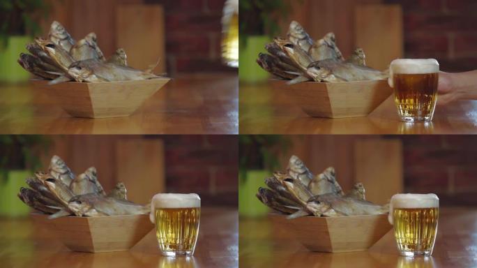 一杯冷新鲜啤酒放在木条上。小吃啤酒。带干鱼的木碗。