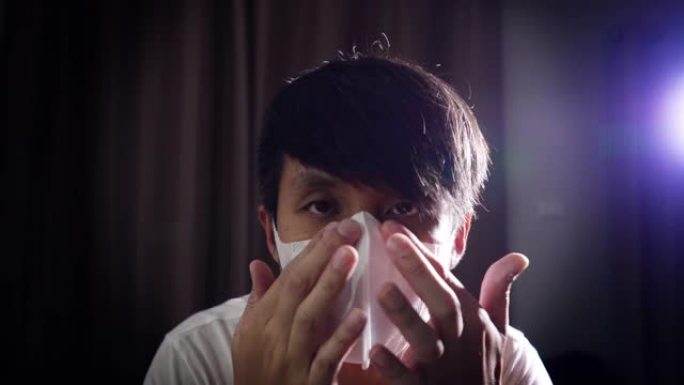 亚洲男子戴着外科口罩在黑暗的房间里保护电晕病毒。