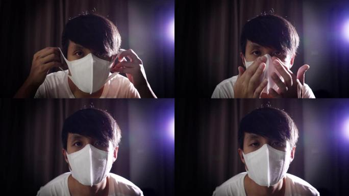 亚洲男子戴着外科口罩在黑暗的房间里保护电晕病毒。