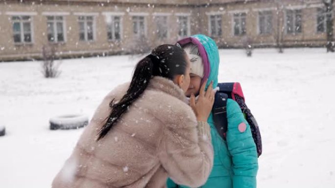 下雪了，妈妈抱着女儿，冬天走路去上学。