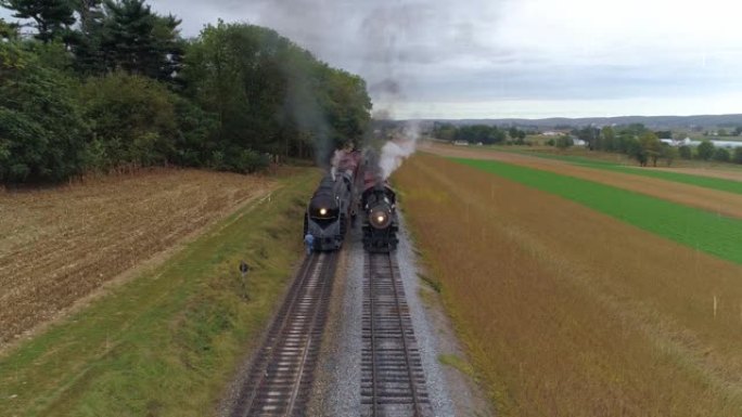 两个蒸汽机车并排蒸腾的空中俯视图，在下雨天移至侧视图