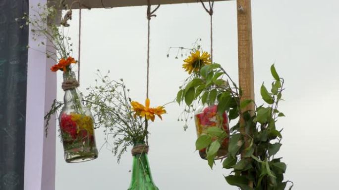 瓶子里的植物和鲜花挂在风中，绳子挂在风中。