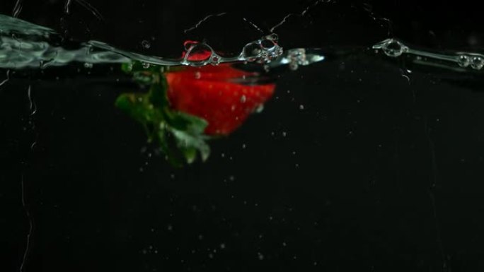 新鲜草莓以慢动作落在水中。在黑色背景上。