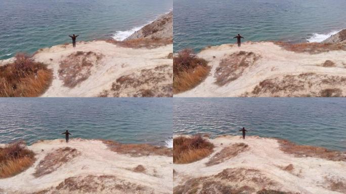 考虑到环境，一名年轻女子站在海洋上方的悬崖边缘练习瑜伽。体式、能量和冥想