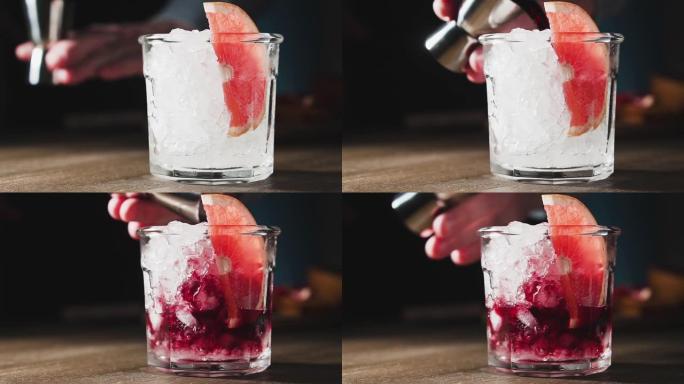 调酒师将红酒倒入带有葡萄柚和冰块的玻璃杯中，慢动作。葡萄柚鸡尾酒，特写。