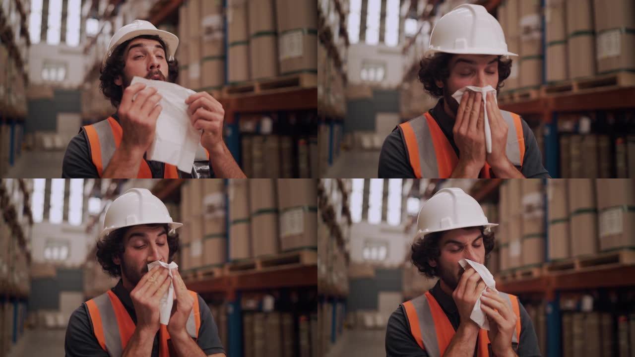穿着白色安全帽和反光夹克的变态过敏男性工厂工人站在仓库里，用纸巾吹鼻子