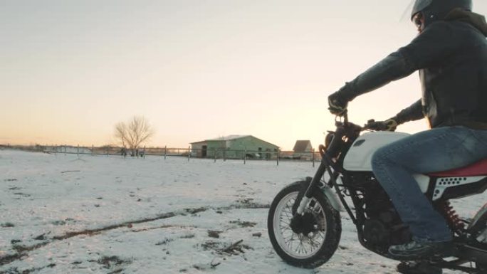 摩托车手在雪地里做轮胎倦怠，慢动作。专业摩托车手在日落时在雪地上漂移并打开摩托车。骑自行车的人在摩托