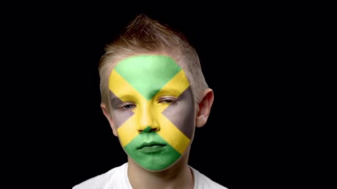 牙买加足球队的悲伤球迷。一个脸上涂着民族色彩的孩子。