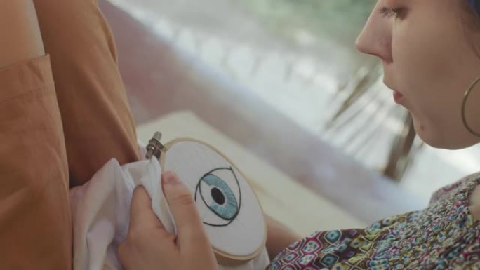 女人在白布蕾丝框侧视上绣眼纹特写。