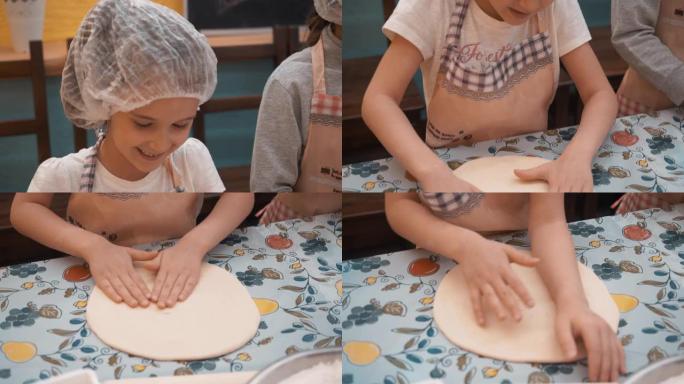 年轻女孩在烹饪学校的烹饪课上滚动意大利披萨面团。快乐的女孩在面包店学校的烹饪课上准备圆形的馅饼。学校