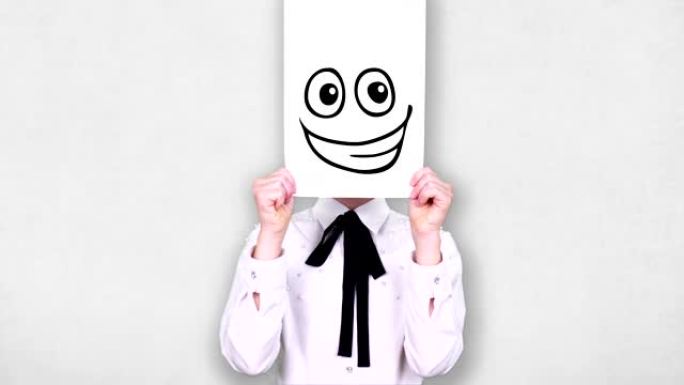 肖像，少年拿着白纸纸，上面有愚蠢的笑脸画，动画，遮住脸。情感，想象力，创造力，成功的想法概念