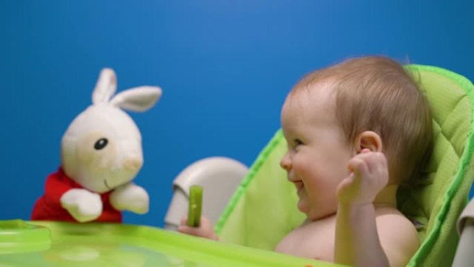 可爱的孩子宝宝吃绿色新鲜芹菜棒玩兔子娃娃