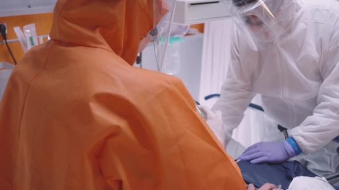 身穿防护服的医生为患有冠状病毒中等倾斜镜头的患者戴上氧气面罩