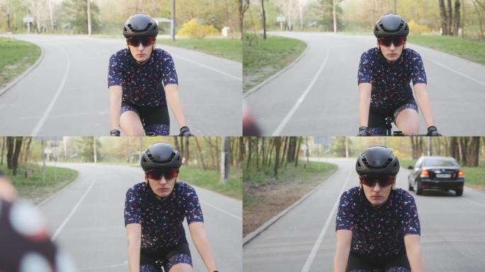 专注的女自行车手在公园骑自行车。前视图。戴着黑色头盔和眼镜。慢动作