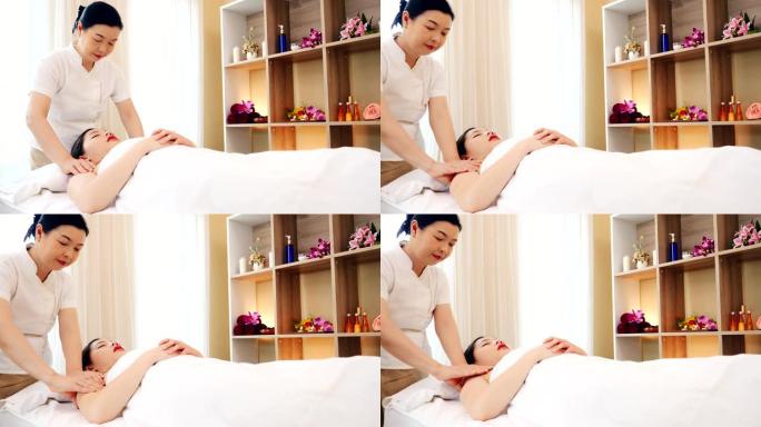 亚洲妇女放松，同时接受一个专业的按摩治疗美容和健康。专业按摩师为亚洲女性按摩后背和肩膀