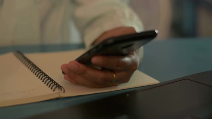 女商人用手机在办公桌上写字。