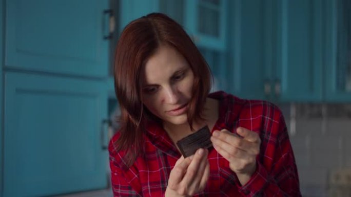 穿着红色衬衫的30多岁年轻女子在蓝色厨房上阅读化妆品面膜的指导。女人在家美容。