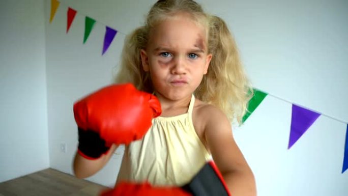 愤怒好斗的女孩用拳击手套打了一拳。孩子脸上有淤青