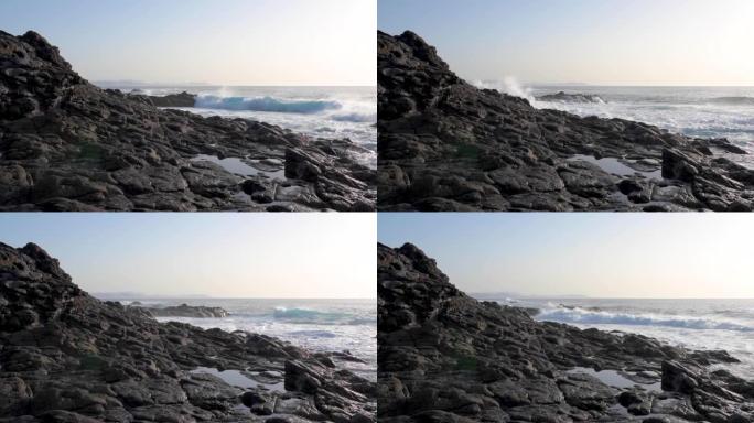 兰萨罗特岛的岩石海岸线与波涛汹涌的海面和晴朗的金色天空