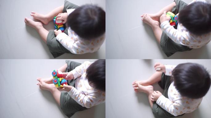 亚洲男婴在家玩玩具车的俯视图。