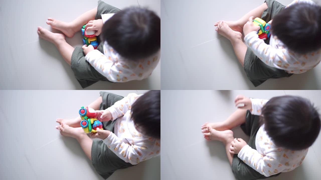 亚洲男婴在家玩玩具车的俯视图。
