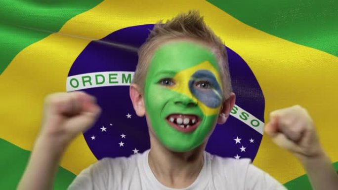 巴西国旗背景上的快乐粉丝。有着民族色彩的脸的快乐男孩。