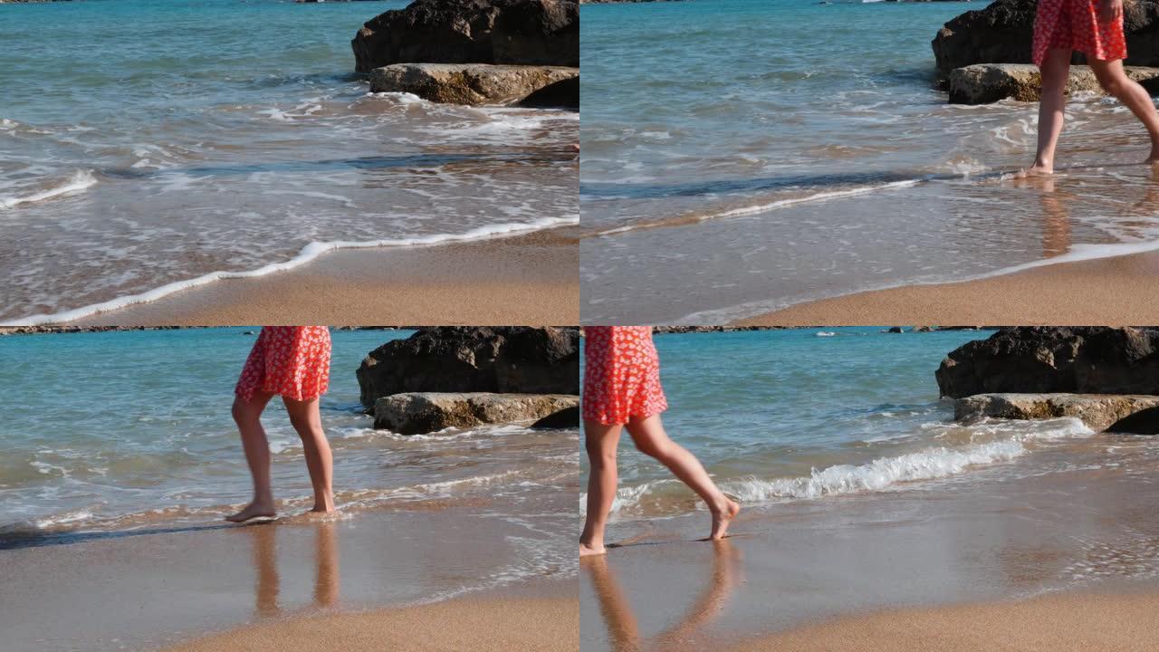 女人在沙滩上纤细的腿。年轻迷人的女孩走在沙滩上。穿着红色连衣裙的白人女孩，纤细的腿沿着海边散步。