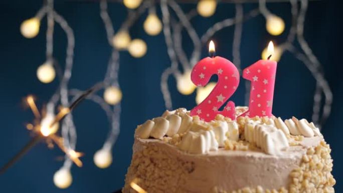 生日蛋糕，蓝色背景上有21号粉色蜡烛和烟火。慢动作和特写视图