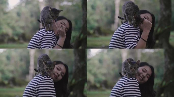 亚洲女孩坐在森林里，可爱的猫站在她的肩膀上。