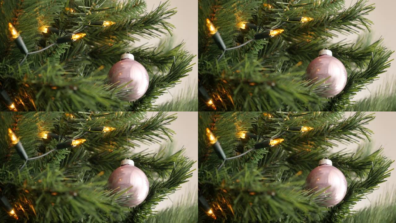 倾斜在人造圣诞树4K上闪亮的粉色玻璃摆设