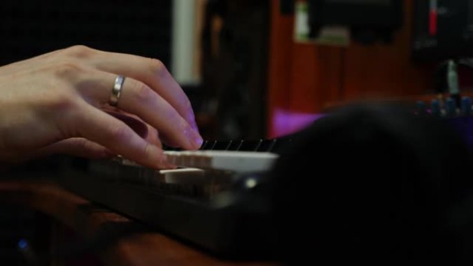 在家庭音乐工作室中，男性双手在电子钢琴midi键盘上演奏。手指在录音室弹钢琴。声音作曲家创作浪漫歌曲
