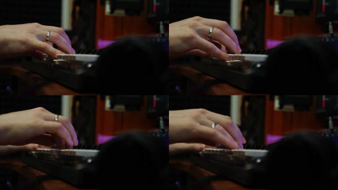 在家庭音乐工作室中，男性双手在电子钢琴midi键盘上演奏。手指在录音室弹钢琴。声音作曲家创作浪漫歌曲