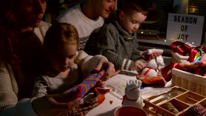 父母和他们的两个孩子一起剪旧袜子和制作玩具雪人