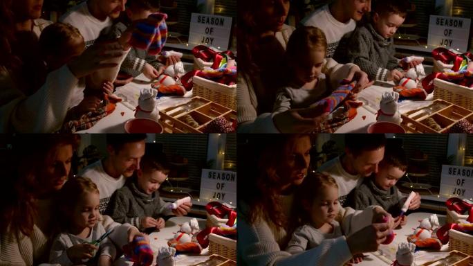父母和他们的两个孩子一起剪旧袜子和制作玩具雪人