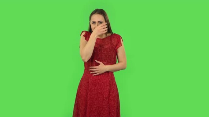 穿着红色连衣裙的温柔女孩正在感冒，喉咙痛和头，咳嗽。绿屏
