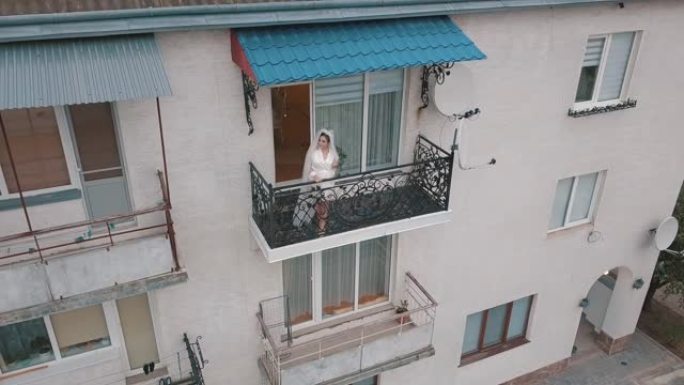 穿着睡衣的新娘站在她家的阳台上。婚礼早上。鸟瞰图